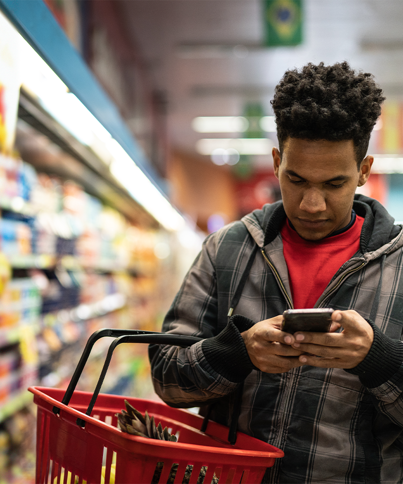 A man looks at his text messages while shopping for groceries.