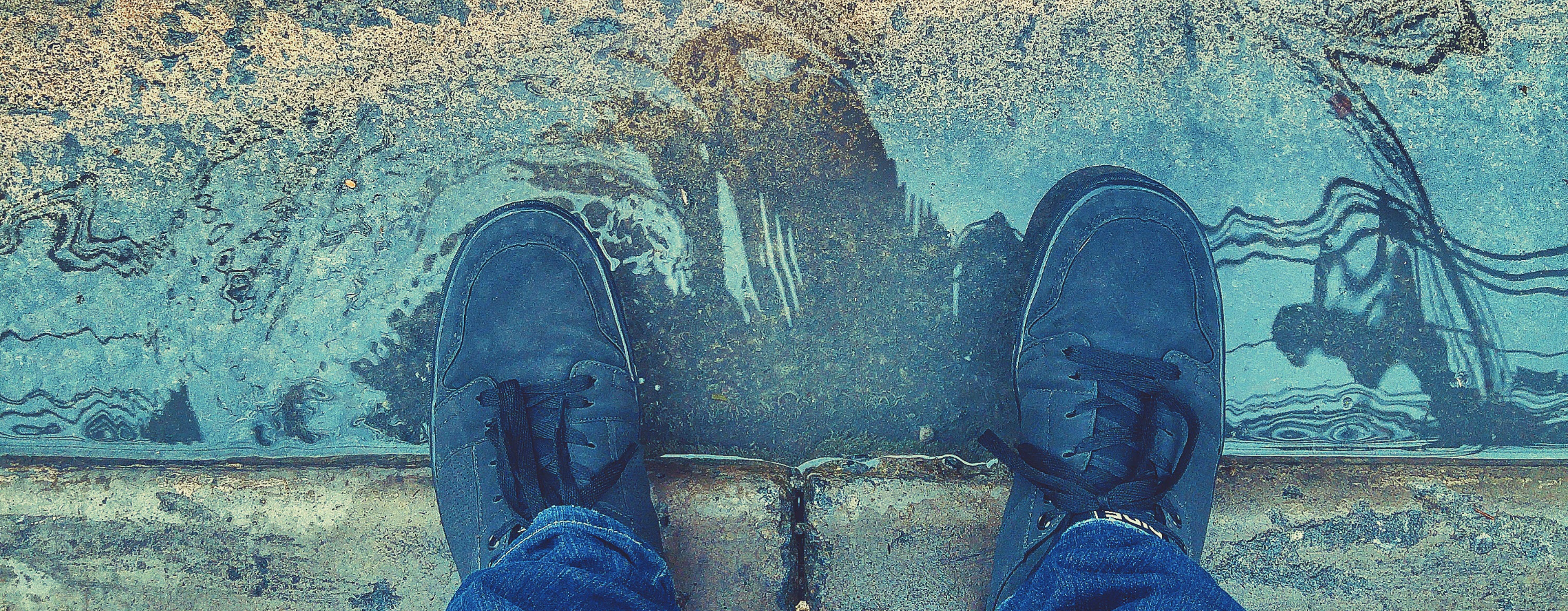 feet standing in a puddle by the sidewalk